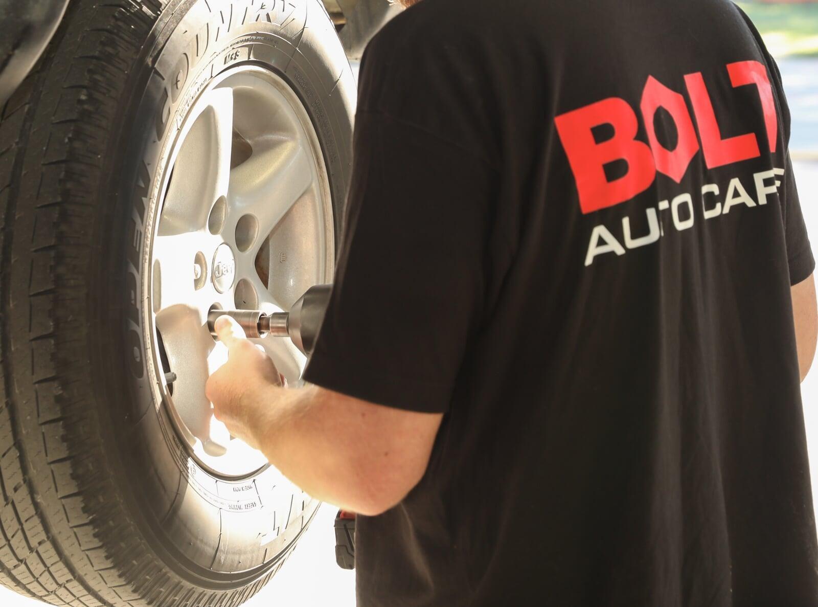 <Bolt Auto Care employee working on a tire>