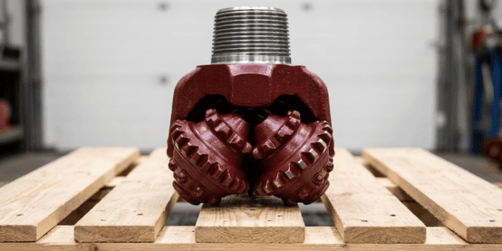 Tricone drill bits lined up on a warehouse pallet