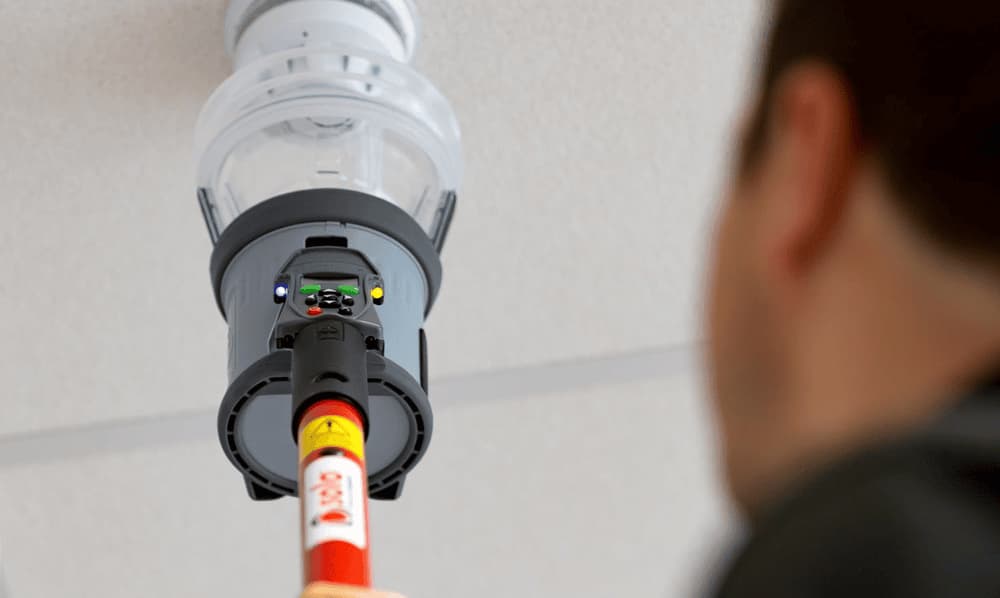 Man holding a Testifire all-in-one detector tester, emphasizing active maintenance of smoke and CO detectors. Man holding a Testifire all-in-one detector tester, emphasizing active maintenance of smoke and CO detectors.
