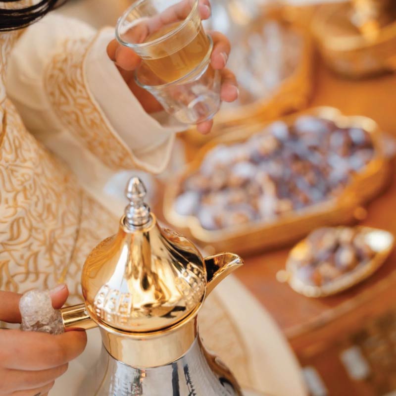 LOriental hostess dressed in Arabian traditinal clothes serving Arabian coffee with stuffed dates at an event