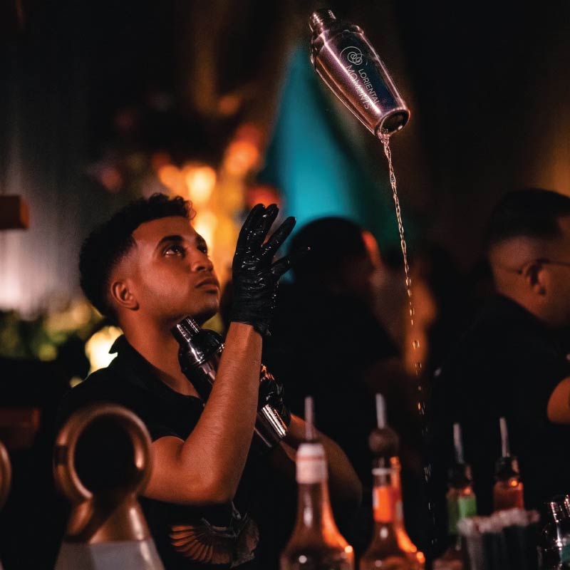 LOriental mixologist performing bottle flair at a theatrical non-alcoholic live bar in Egypt