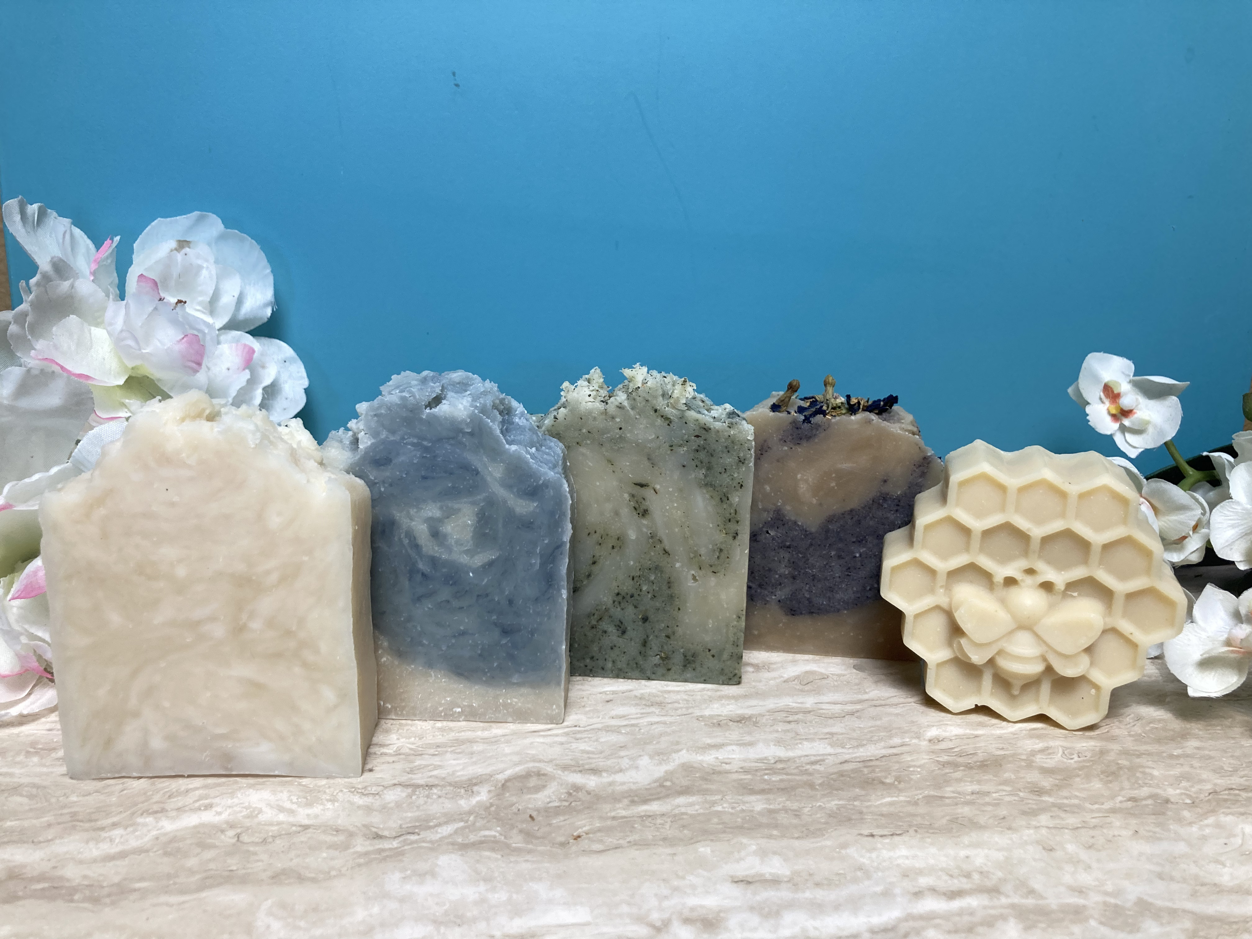 : Five Sudsables signature soaps on marble with flowers and aqua background : Five Sudsables signature soaps on marble with flowers and aqua background