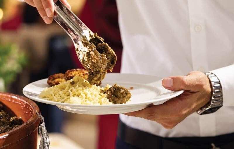 Employee serving lunch at a corporate open buffet catered by LOriental