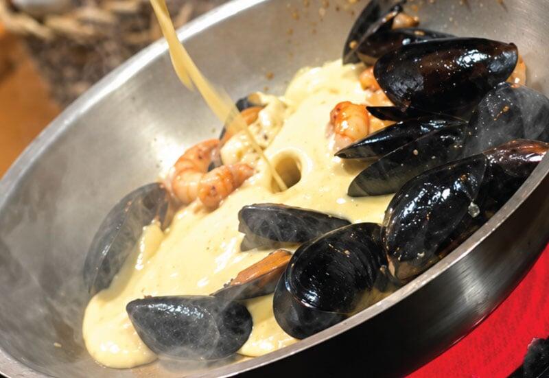 Close-up shot of hot pan swirling with mussels, shrimp and cream Close-up shot of hot pan swirling with mussels, shrimp and cream
