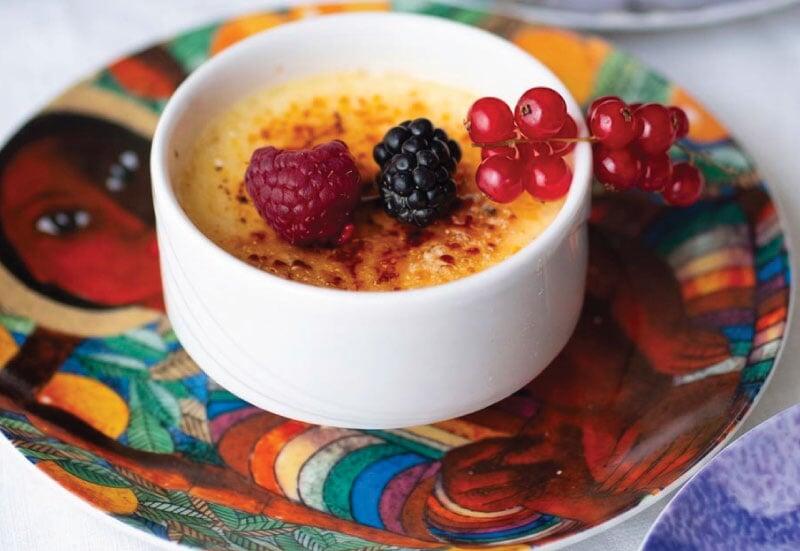 Vanilla crème brûlée with fresh berries served by LOriental at a Dominican Republic Ambassador seated lunch in Egypt, presented on a colorful Dominican cultural plate. 