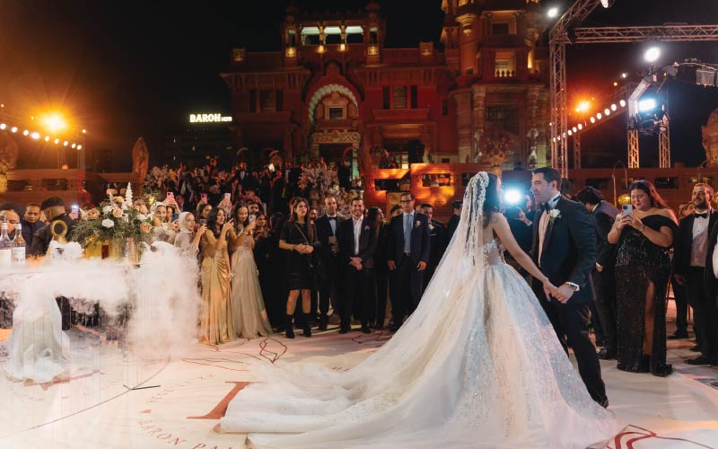 Bride and groom first dance at wedding at Baron Empain Palace, crowd watching behind them