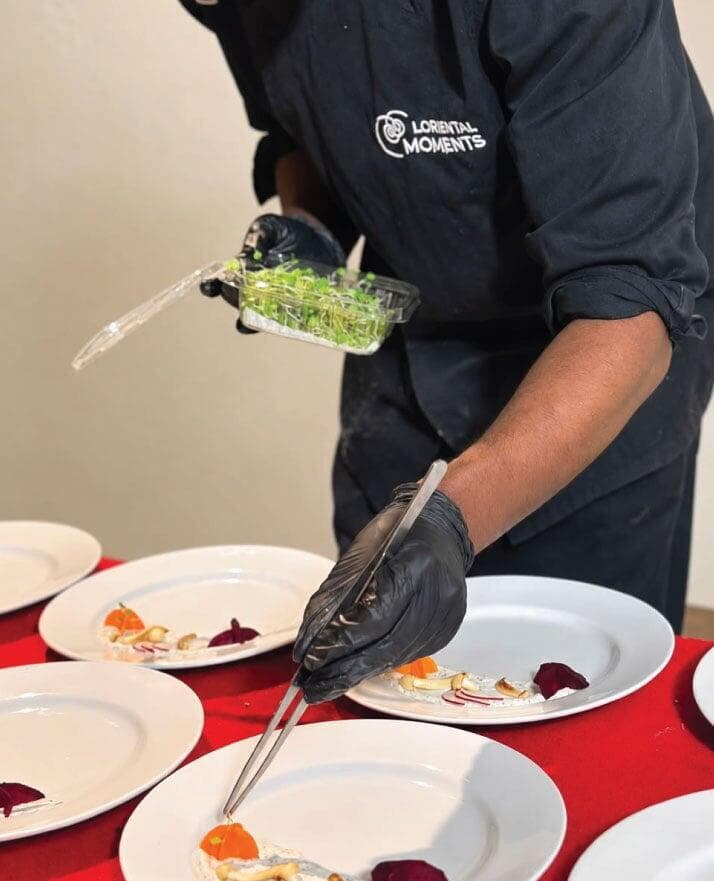LOriental chef adding garnish to plate