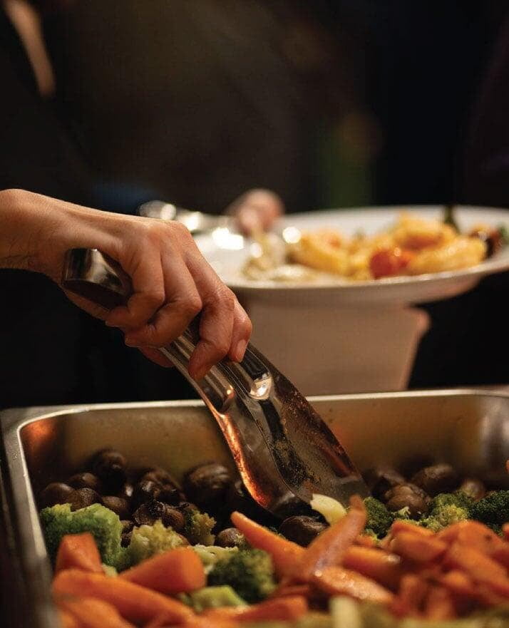 Guest serving roasted vegetables in plate