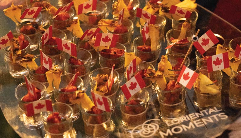Pineapple glazed teryiaki chicken skewers in shot glasses on LOriental branded tray with Canada flags at Canada Day 2026