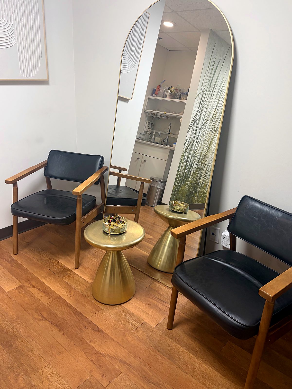 Bright waiting area with leather chairs, gold side tables and an arched mirror at Vancouver Green Spa