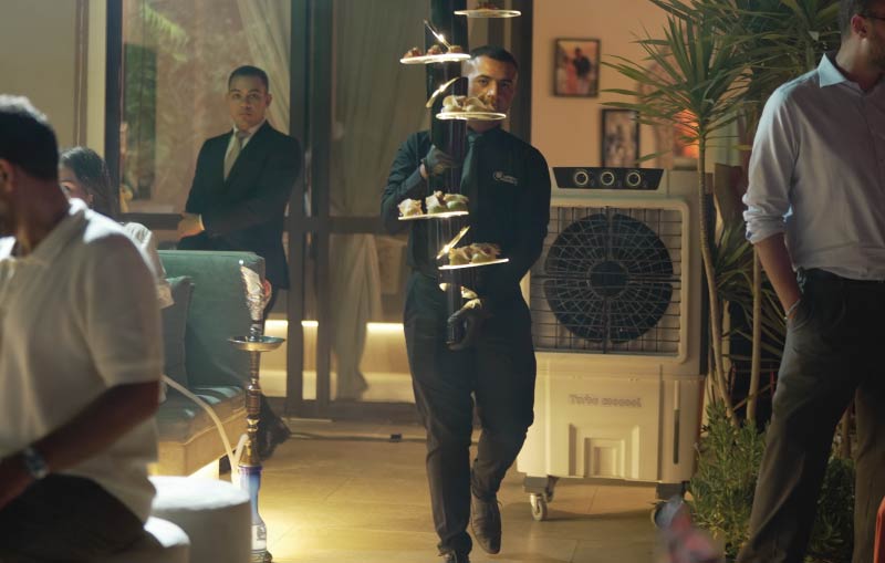 LOriental waiter carrying a theatrical presentation system at a home birthday