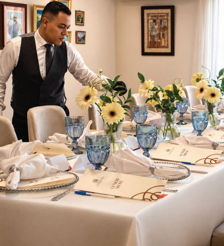 LOriental staff member making final adjustments to table setup at a seated dinner
