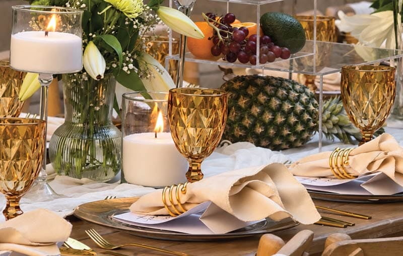 Elegant seated dining table setup with candles, florals, gold glassware and fresh fruit styling Elegant seated dining table setup with candles, florals, gold glassware and fresh fruit styling
