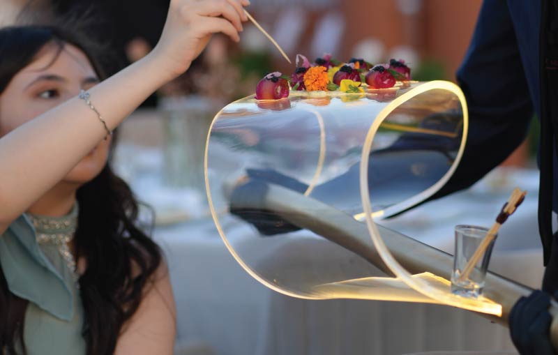 LOriental waiter serving salmon gravlax from theatrical platform Infinity Wave designed and manufactured by LOriental